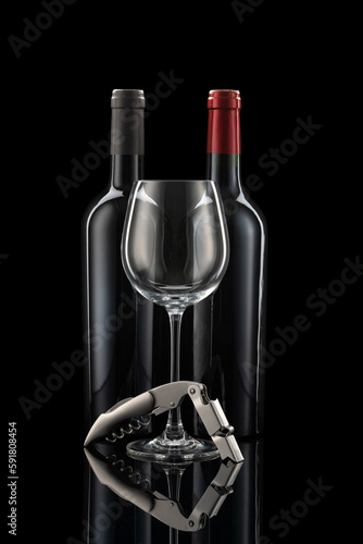 Two wine bottles next to each other, a wine glass and wine cutlery in front of a black background