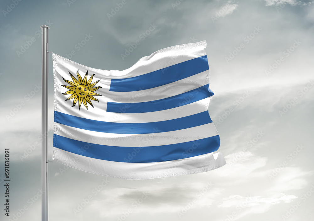 Fototapeta premium Uruguay national flag cloth fabric waving on beautiful sky Background.