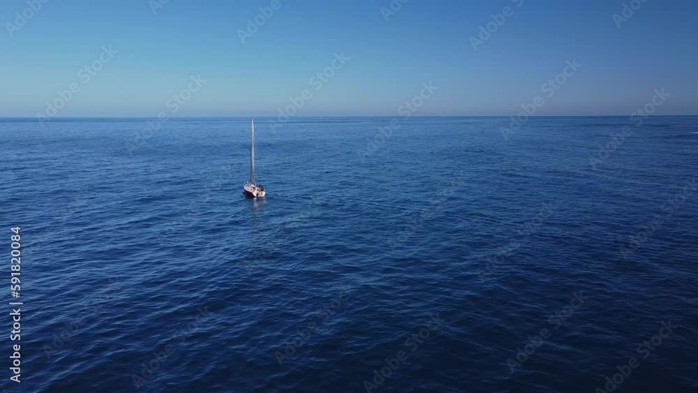 Lone little boat sailing across a beautiful dark blue sea under a clear sky at sunset Lone little boat sailing across a beautiful dark blue sea under a clear sky at sunset