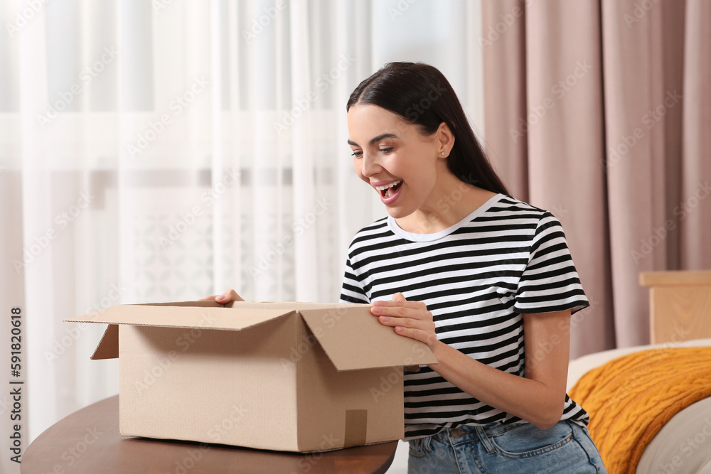 Emotional young woman opening parcel at home. Internet shopping Emotional young woman opening parcel at home. Internet shopping