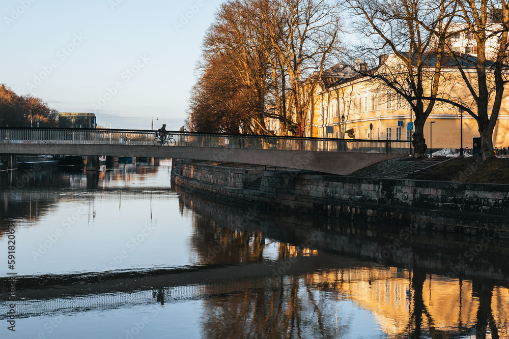 Cyclist on Kirjastosilta bridge in Turku, Finland in spring during golden hour in the morning.
