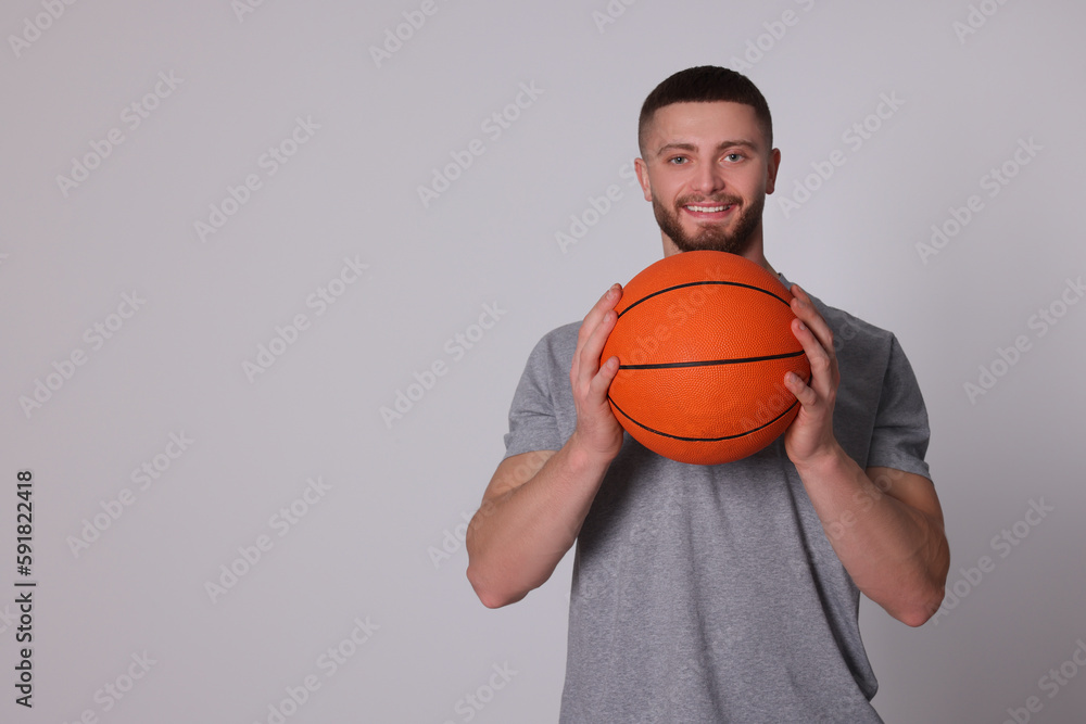 Athletic young man with basketball ball on light grey background. Space for text Athletic young man with basketball ball on light grey background. Space for text
