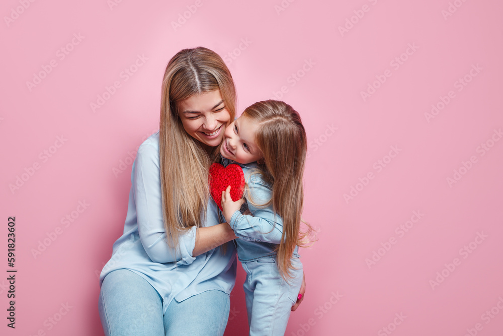 I love my mom. Mothers day .Close-up portrait little daughter hugs and kisses her mom on pink background.