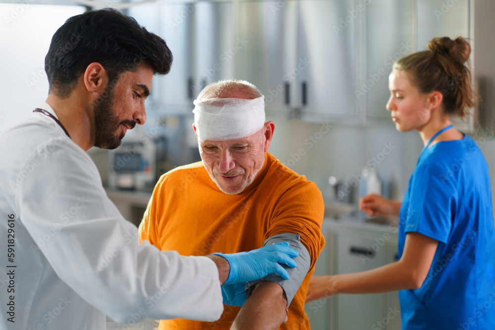 Obraz premium Young doctor and nurse treating injury of senior man.