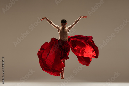 Butterfly. Young handsome man, professional ballet dancer performing shirtless with red fabric against grey studio background. Concept of art, classical dance, inspiration, creativity, choreography