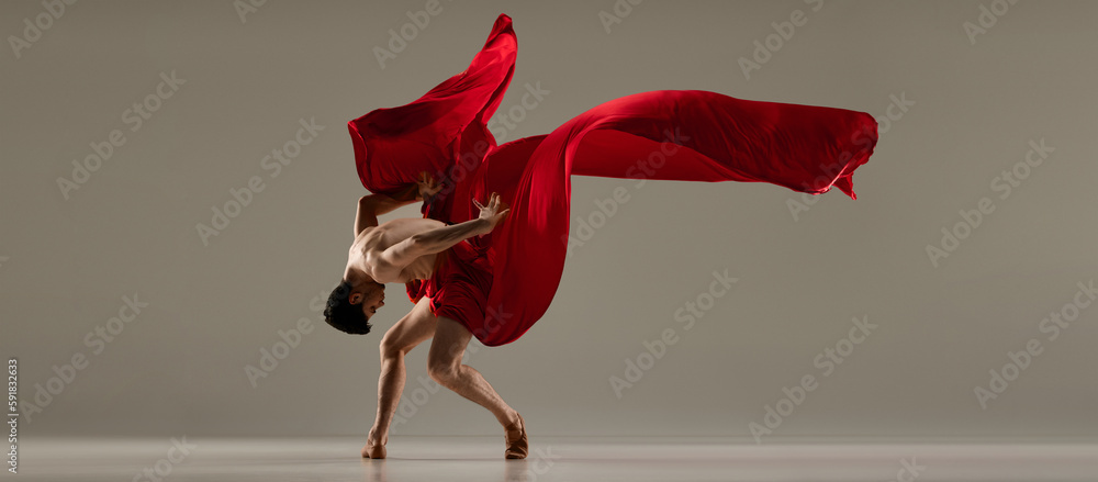 Talented performance. Handsome man, ballet dancer dancing with red silk fabric against grey studio background. Concept of art, classical dance, inspiration, creativity, fashion, beauty, choreography - obrazy, fototapety, plakaty 