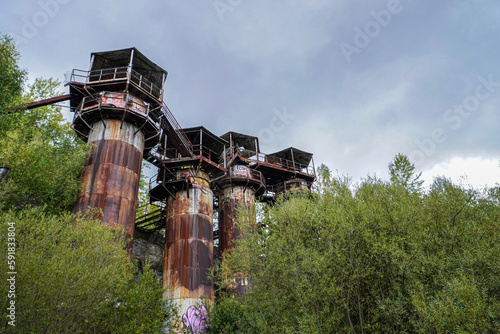 Old abandoned rusty quarry ruins overgrown by forest