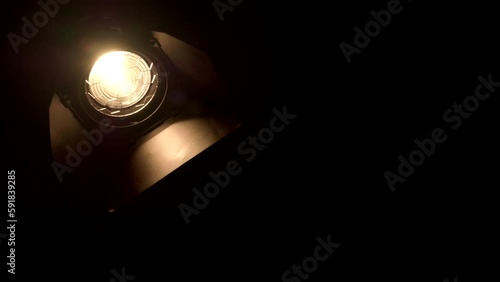 Video studio Fresnel lens spotlight on black background. Lights slowly turn on and off.