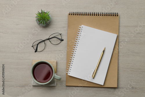 Ballpoint pen  notebooks and cup of tea on wooden table  flat lay