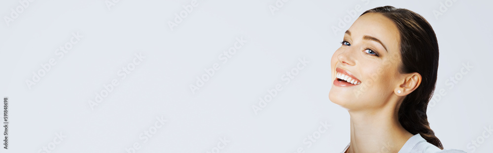 Obraz premium Portrait of happy excited smiling beautiful young woman with open mouth, looking side away up, on light grey gray. Brunette laughing girl at studio image. Wide banner composition.