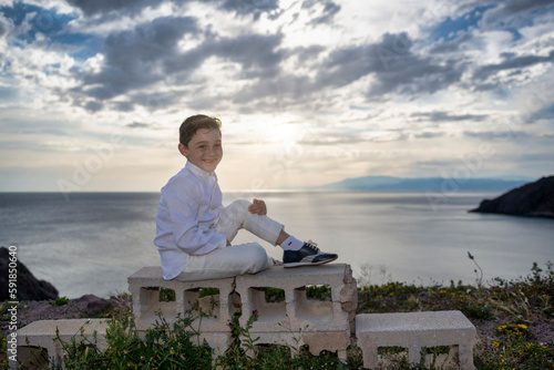 Unwavering Confidence: A Handsome Boy Poses on the Cliff at Sunset