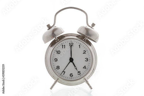 small metal alarm clock on a white background, time is 5 o'clock