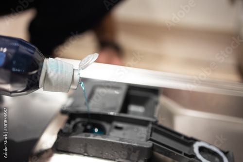 Close up of a man pouring a rinse into the compartment of a dishwasher. Household chores, house cleaning, cleaning, repair and maintenance of equipment. Selective focus photo