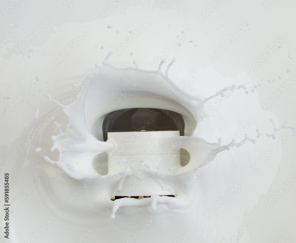 Naklejka premium Cosmetic container white lotion droplet fly splashing. Milk lotion pour float to cosmetic bottle. Moisturizer lotion explosion spill. White background isolated high speed shutter freeze top view