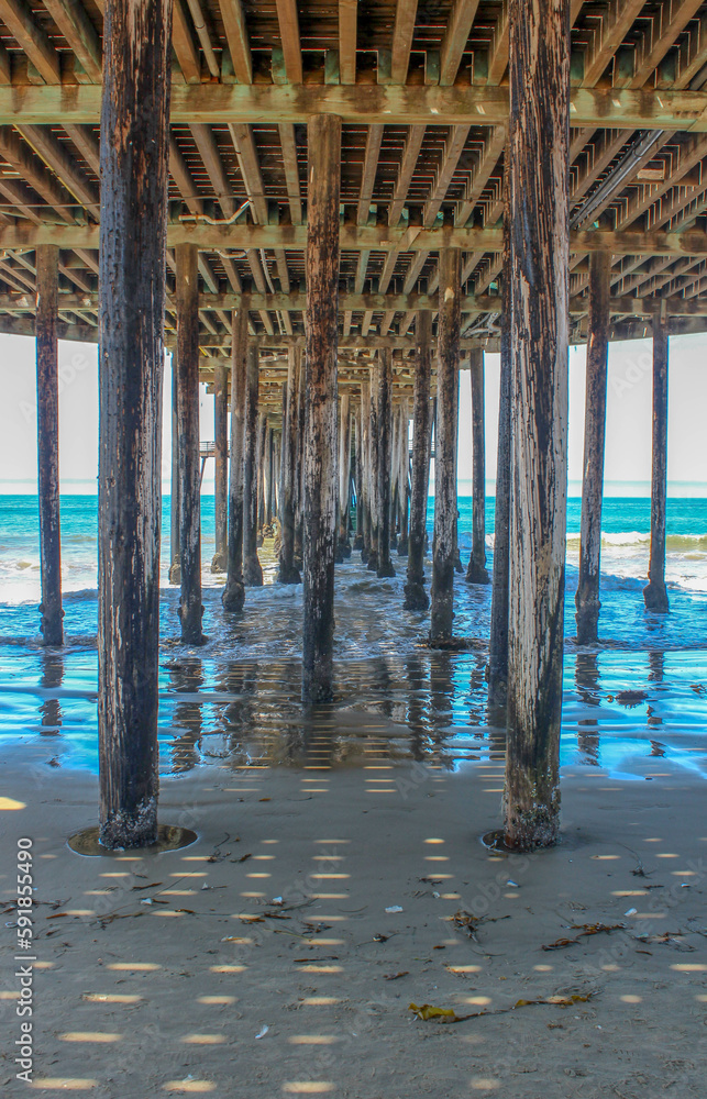 Vertical shot of the wooden logs in the sea under the pier