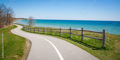 Asphalt road with a wooden fence along the blue sea under the clear sky