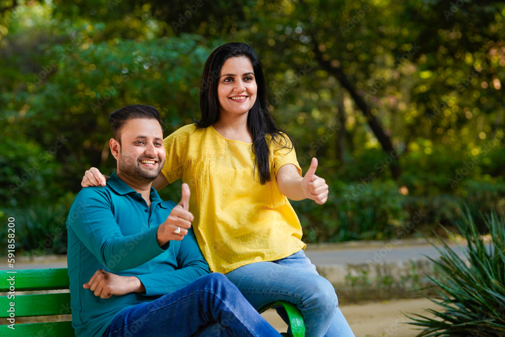 Fototapeta premium Happy young indian man and woman showing thumps up at park.