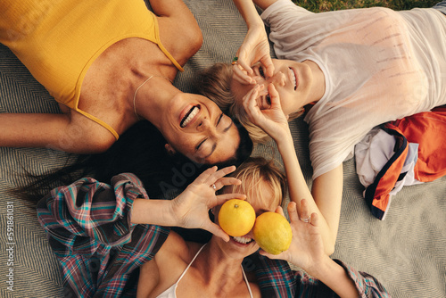 Fun female friends smiling and laughing while lying down in the park photo