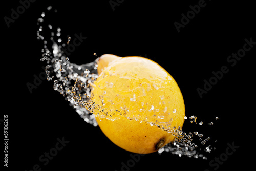 Closeup of the lemon with splashing water against the dark background.