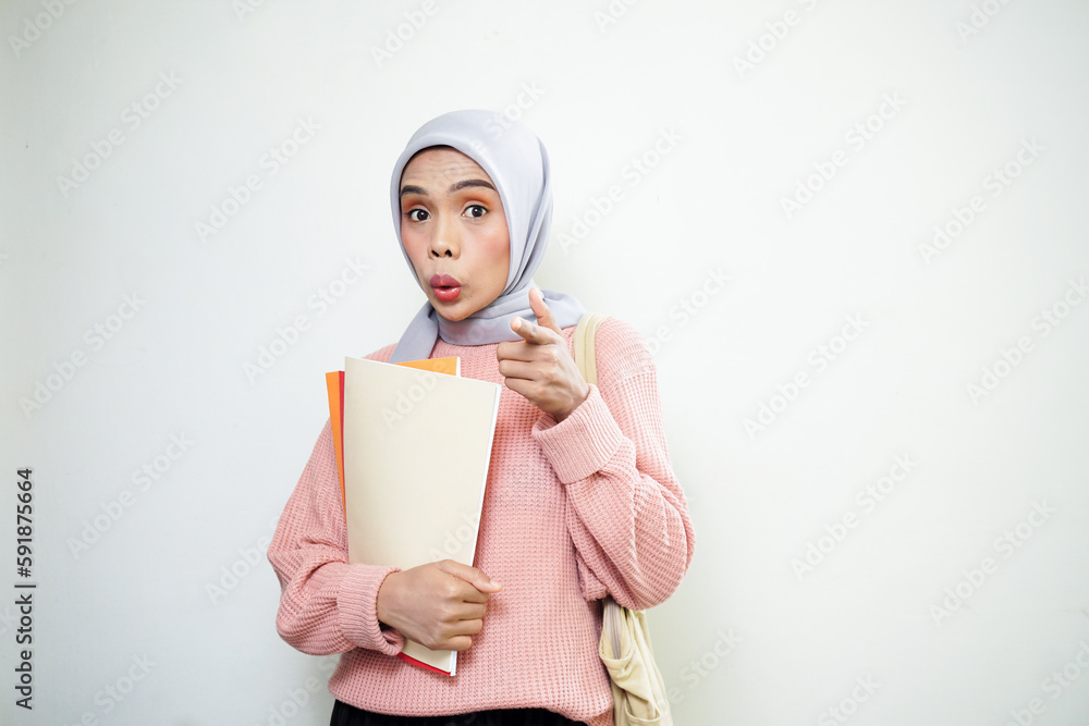 Excited young Asian Muslim woman student in pink sweater with bag, holding book isolated on white background. back to school concept Excited young Asian Muslim woman student in pink sweater with bag, holding book isolated on white background. back to school concept