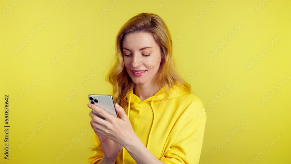 Woman smiling, phone scroll, happiness and swiping on online dating app. Mobile smartphone chat wifi and happy female lady for social media and internet, studio shot isolated on yellow background Woman smiling, phone scroll, happiness and swiping on online dating app. Mobile smartphone chat wifi and happy female lady for social media and internet, studio shot isolated on yellow background