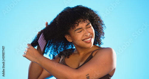 Frustrated, knot and black woman with comb for hair on blue background with problem, hairstyle frizz and damage. Beauty salon, hairdresser and sad girl brush afro for wellness, grooming and cosmetics