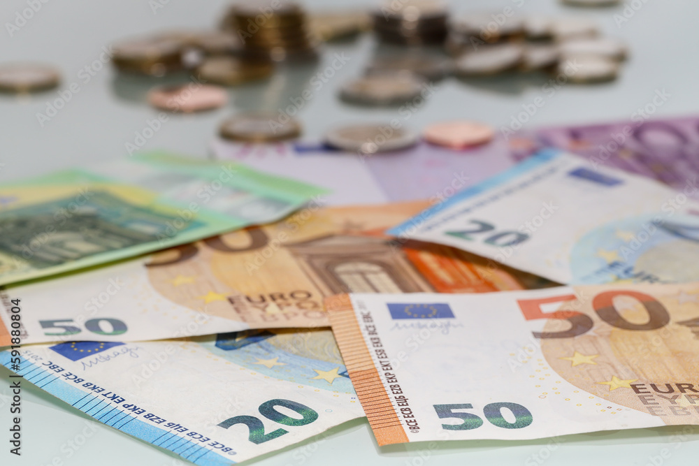 Shallow focus shot of euro banknotes with blurred coins i the background Shallow focus shot of euro banknotes with blurred coins i the background