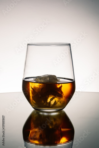 Iced Alcohol drink in a glass cup with reflection on a mirror surface