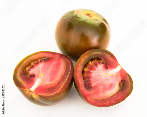 black tomatoes and two halves on white background