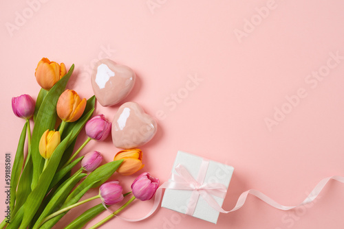 Happy Mother's day concept with tulip flowers, heart shape and gift box on pink background. Top view from above