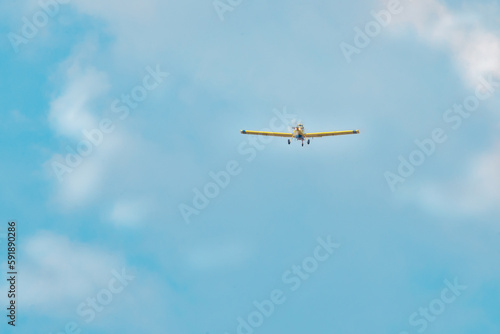 A light aircraft flies with side lights on, against a blue sky with white clouds, flies after extinguishing a fire in the forest.Special flight