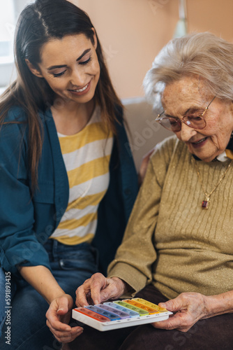 Young woman helping her grandma with her pill box.