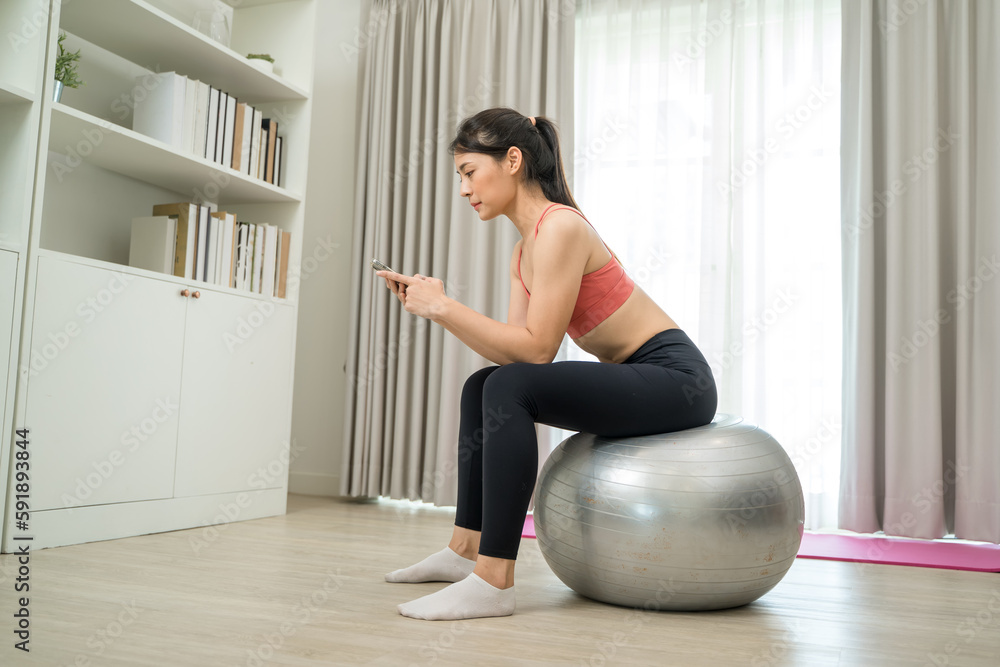 Beautiful woman exercising talking on mobile phone on fitness mat at home,Diet concept,Fitness and healthy lifestyle.