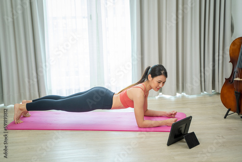 Young woman using tablet pc doing yoga stretching yoga online at home,Entertainment and education on the Internet.