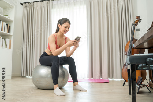 Fototapeta Naklejka Na Ścianę i Meble -  Beautiful woman exercising talking on mobile phone on fitness mat at home,Diet concept,Fitness and healthy lifestyle.