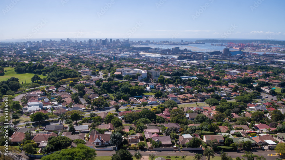 A wide panoramic view of the urban area and city skyline of Durban with harbor and sea in the distance.