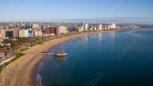 An aerial view of the beach, a jetty into the sea, and hotel skyline along Durban's beachfront.