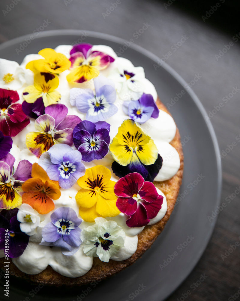 Front view of a homemade cake decorated with fresh pansie Front view of a homemade cake decorated with fresh pansie