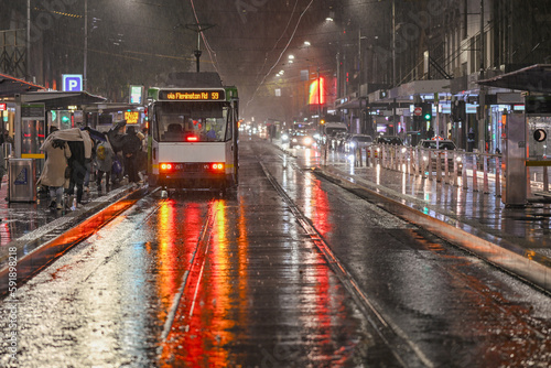 People board a tram on a wet rainy night in Melbourne, Australia