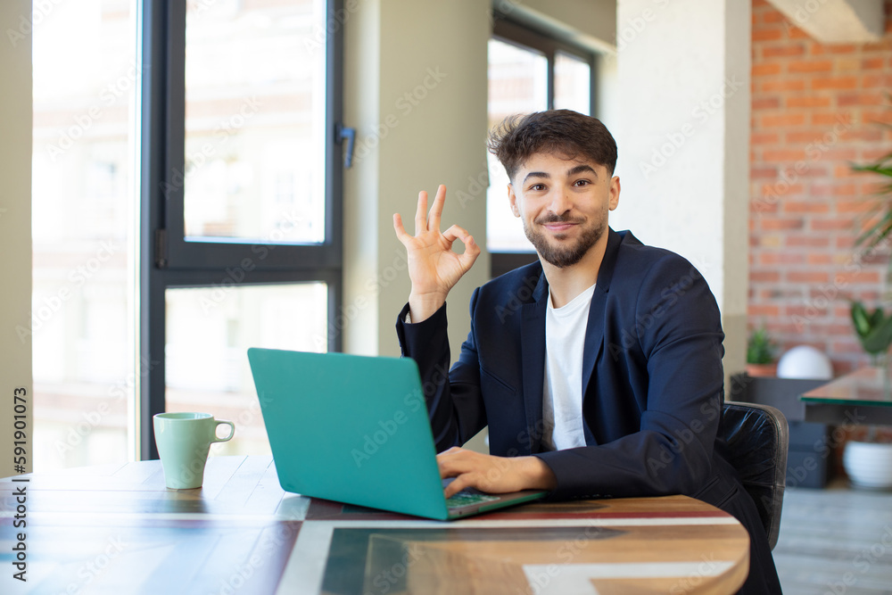 young handsome man feeling happy, showing approval with okay gesture. freelance concept with laptop young handsome man feeling happy, showing approval with okay gesture. freelance concept with laptop