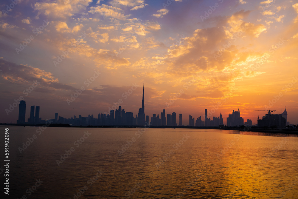 Dubai skyline during sunset. Dubai's skyline sets the scene for a breathtaking sunset, painting the sky with vibrant hues of orange, pink, and gold.