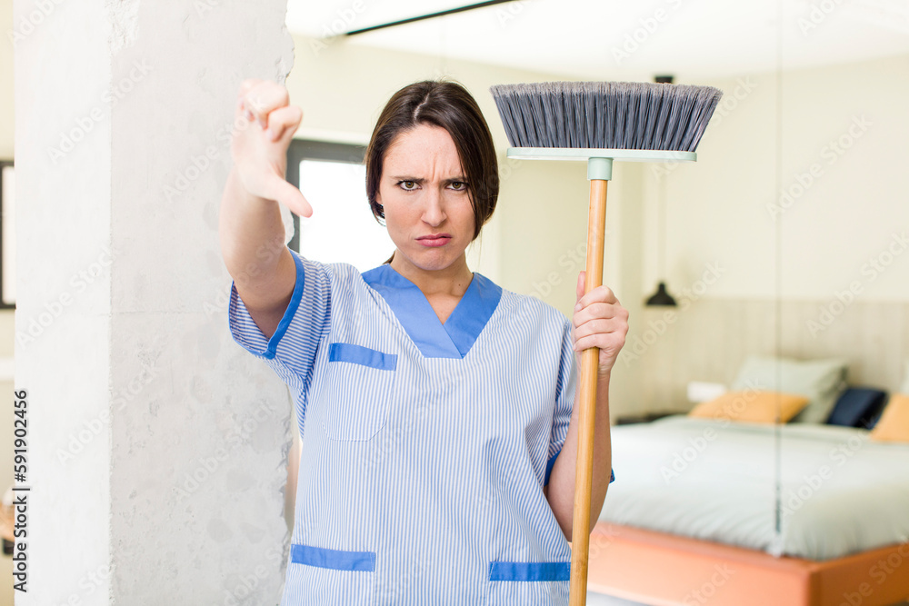 young pretty woman feeling cross,showing thumbs down. housekeeper concept young pretty woman feeling cross,showing thumbs down. housekeeper concept