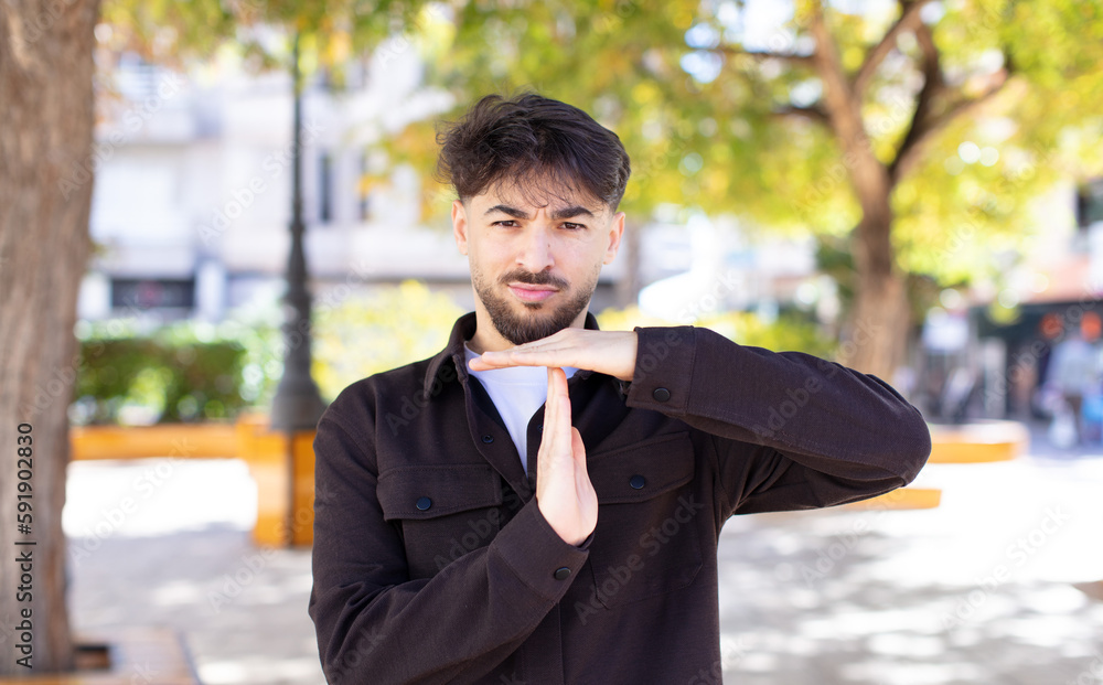 young handsome man looking serious, stern, angry and displeased, making time out sign young handsome man looking serious, stern, angry and displeased, making time out sign
