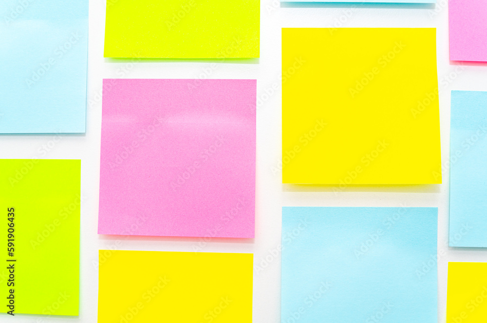 Post it of various colors stuck to a white surface. Notes and memos.