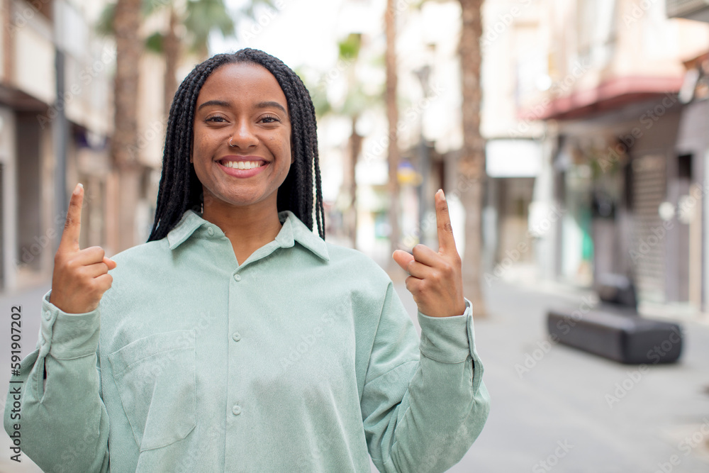 afro pretty black woman feeling awed and open mouthed pointing upwards with a shocked and surprised look afro pretty black woman feeling awed and open mouthed pointing upwards with a shocked and surprised look