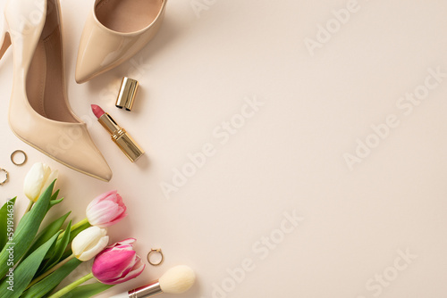 Modern Mother's Day idea. Flat lay top view of high-heels, tulip flowers, lipstick on a pastel beige background with space for text or advert