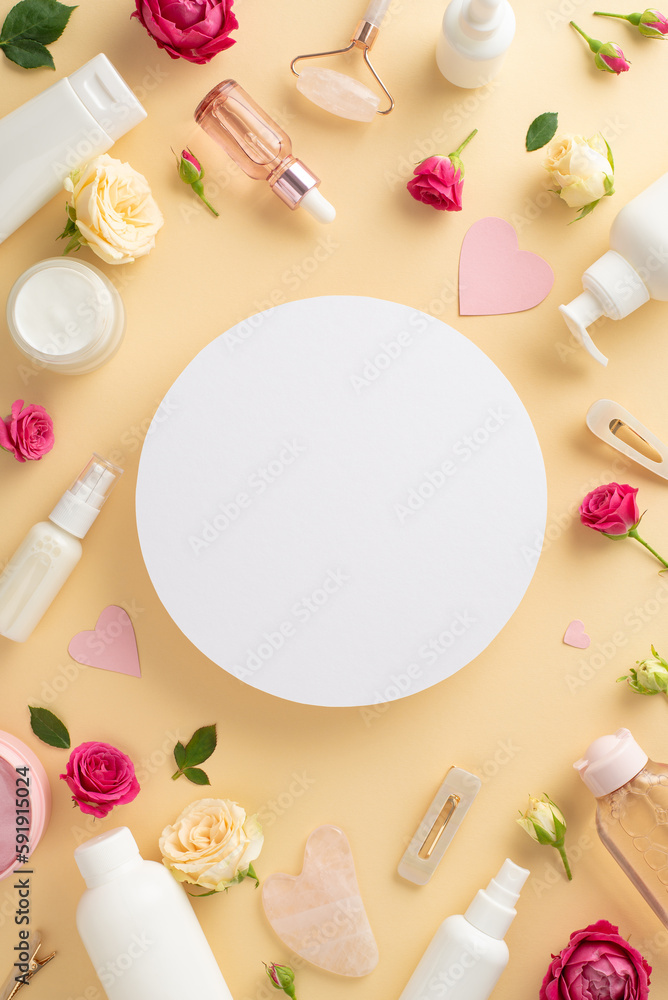 Youthful skin concept. Stylish top view vertical flat lay of cream bottle, serum, and facial roller with fresh roses on a pastel beige background and an empty circle for copyspace or advert Youthful skin concept. Stylish top view vertical flat lay of cream bottle, serum, and facial roller with fresh roses on a pastel beige background and an empty circle for copyspace or advert
