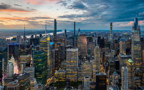 An illuminated midtown of New York City and rainy clouds above in sunset. 