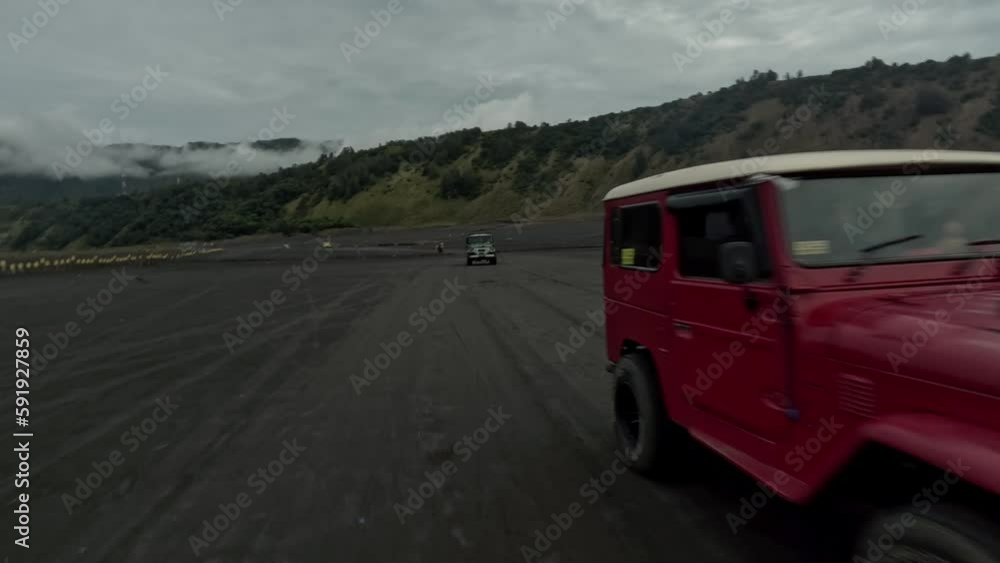FPV drone towards shot between retro colorful jeep SUV riding black volcano lava field dirt dust desert mountain aerial view. Speed automobile rally safari travel extreme sport tropical auto drive 4k FPV drone towards shot between retro colorful jeep SUV riding black volcano lava field dirt dust desert mountain aerial view. Speed automobile rally safari travel extreme sport tropical auto drive 4k