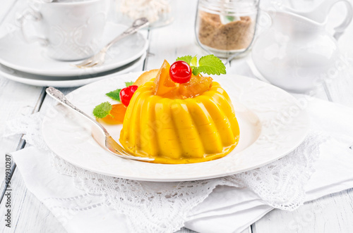 Traditional Italian mango pudding with glaceed cherry served as close-up on a classic design plate